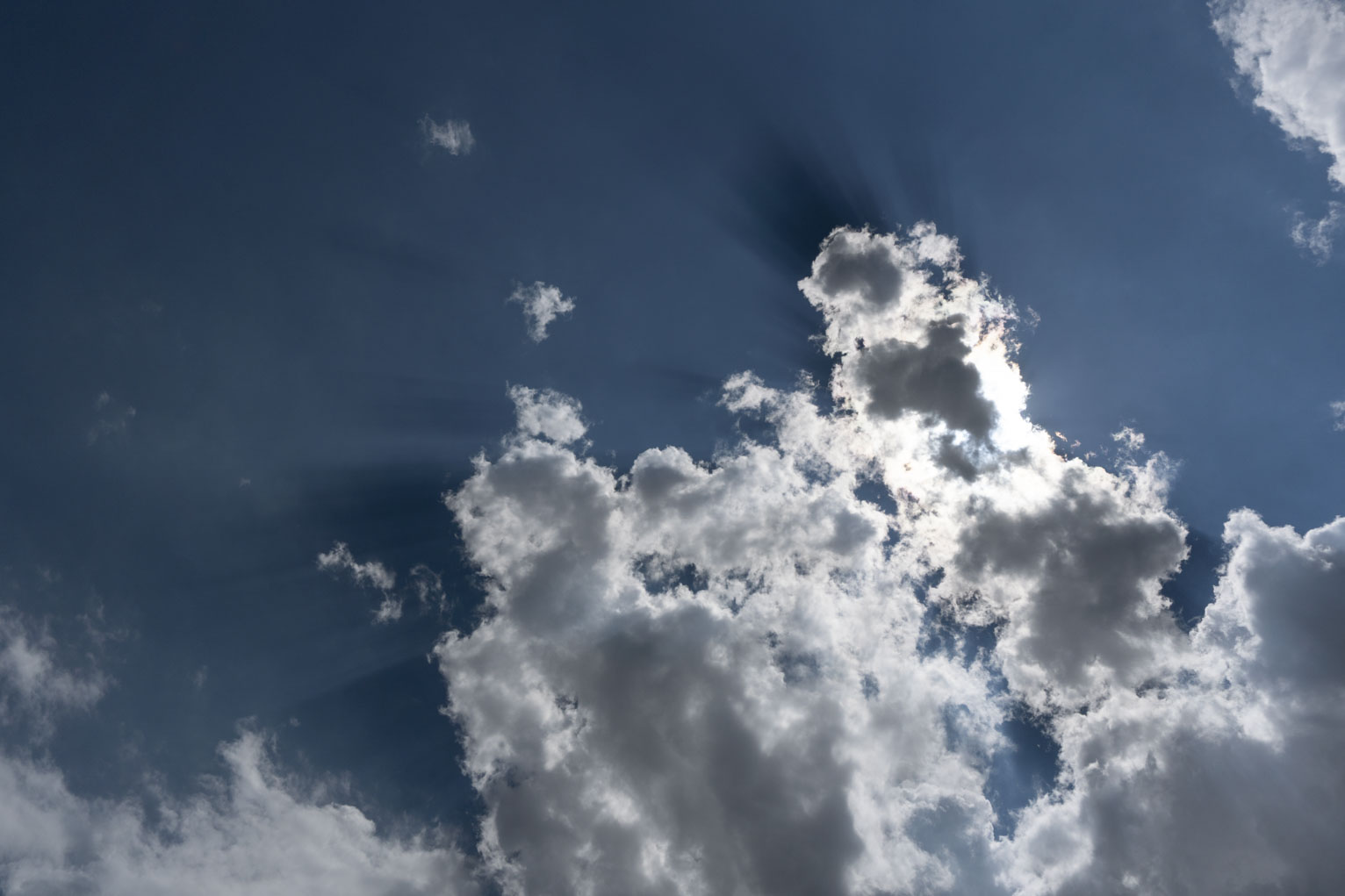 White clouds up in teh blue sky cast strong shadows away from the sun